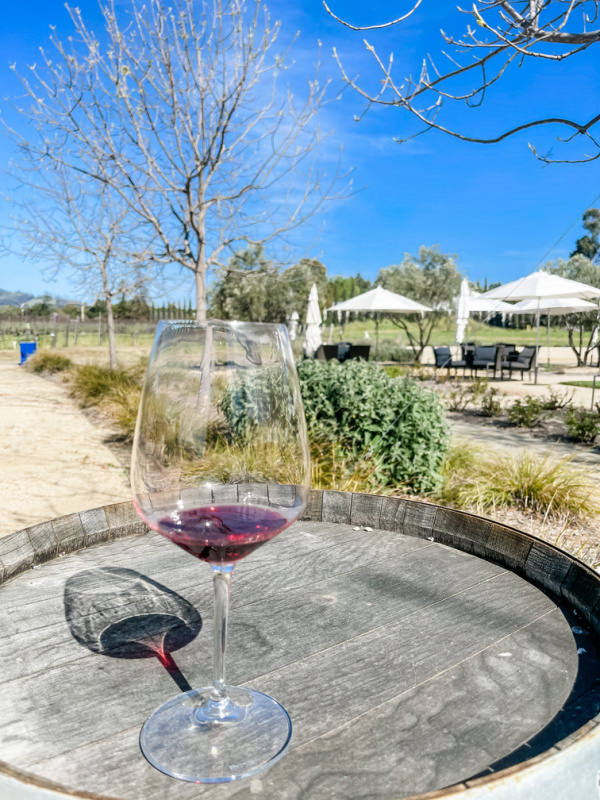 Glass of red wine on barrel in Napa Valley.