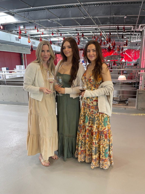 Three women standing inside wine cellar.