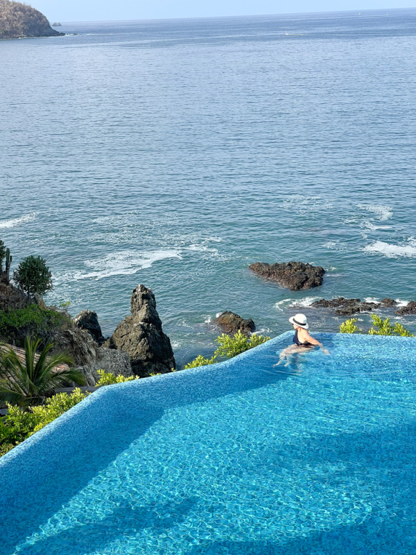 Woman in infinity pool overlooking ocean in Zihautanejo.