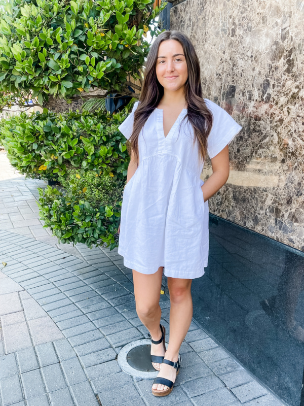 Young woman wearing white linen summer dress.