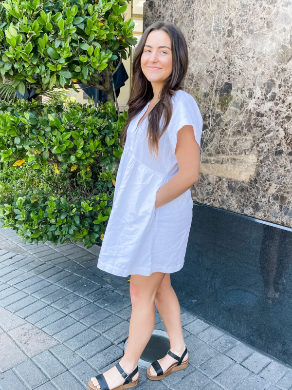 Young woman wearing white linen summer dress.