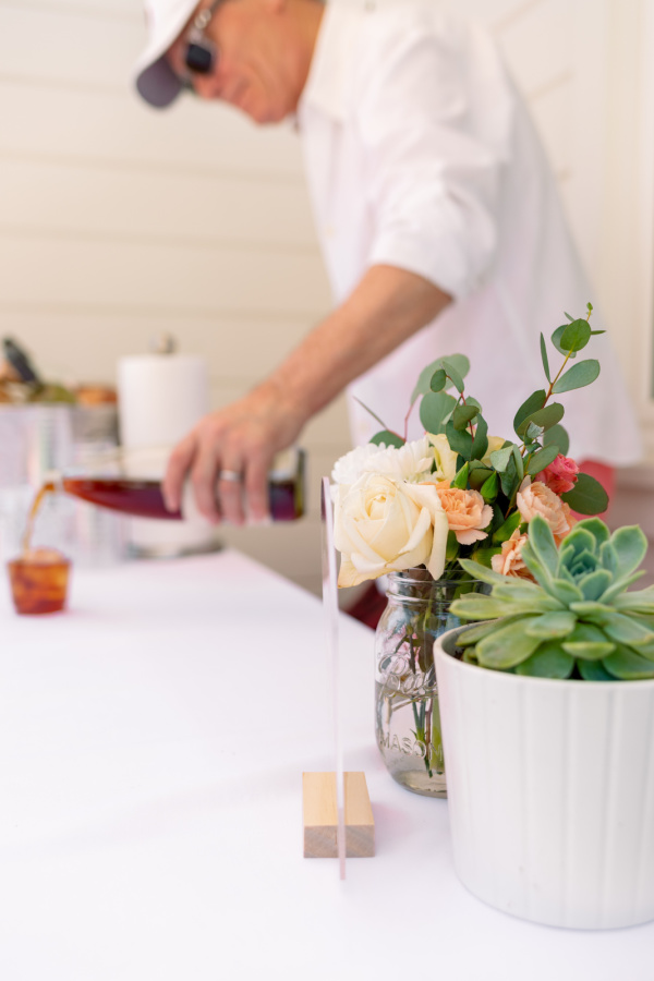 Man pouring drink at baby shower wine bar.