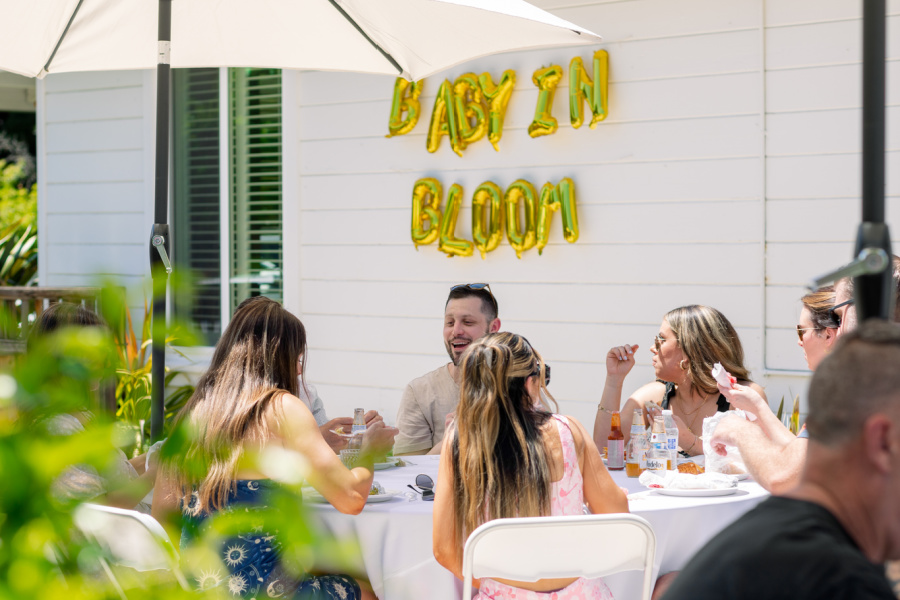 Baby shower guests sitting at outdoor tables.