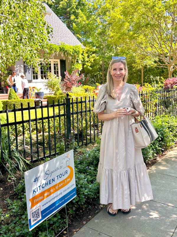 Woman standing in front of pretty house at start of kitchen tour.
