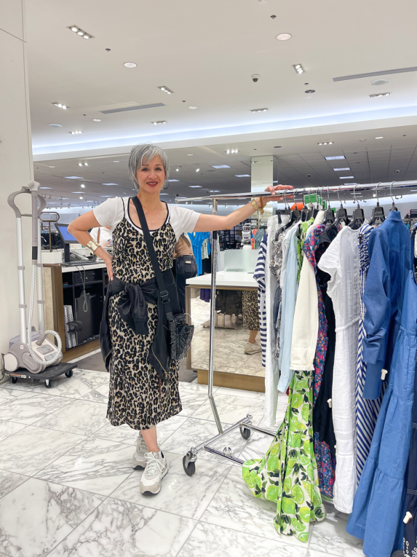 Nordstrom personal stylist standing with rack of women's clothes.