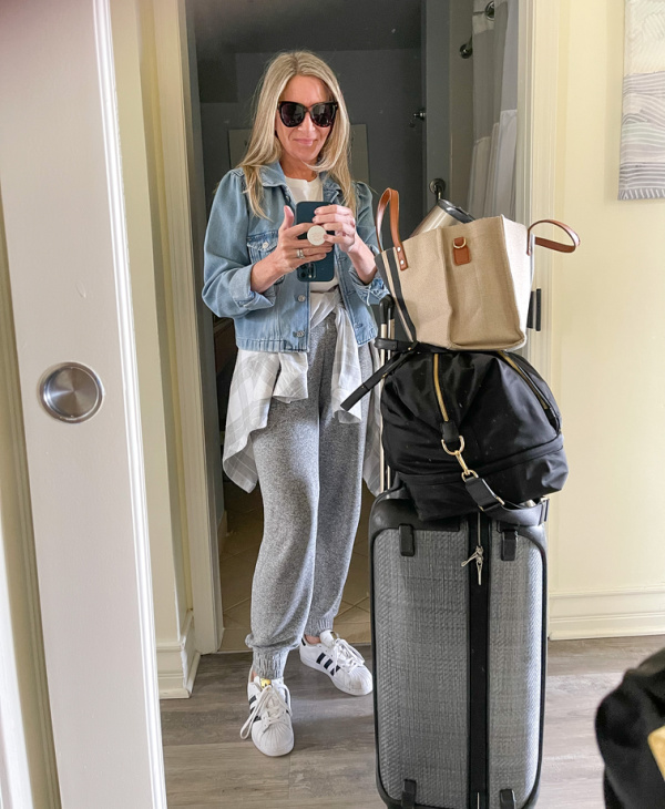 woman standing next to her luggage taking a selfie.