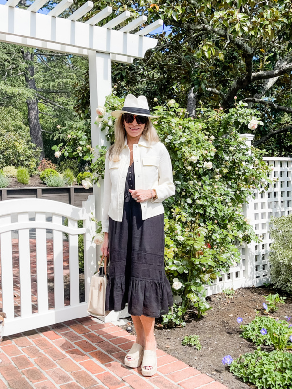 Woman wearing black Rails Kiki dress standing in front of garden gate.