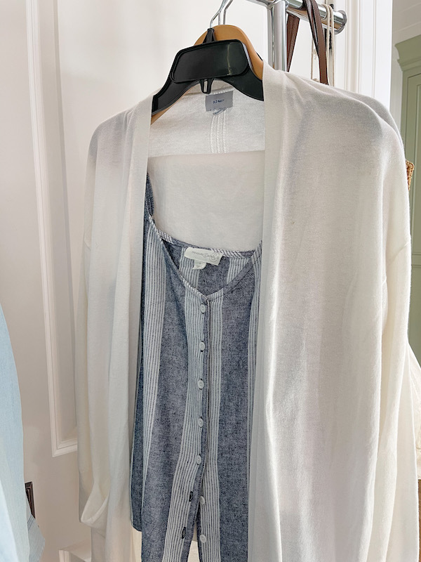 Striped tank top and white open front cardigan on hanger.