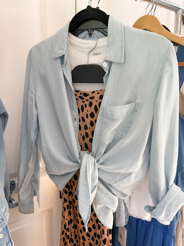 Leopard print skirt, white tee and chambray shirt on hangers on rolling rack. Packing for NAPA VALLEY.