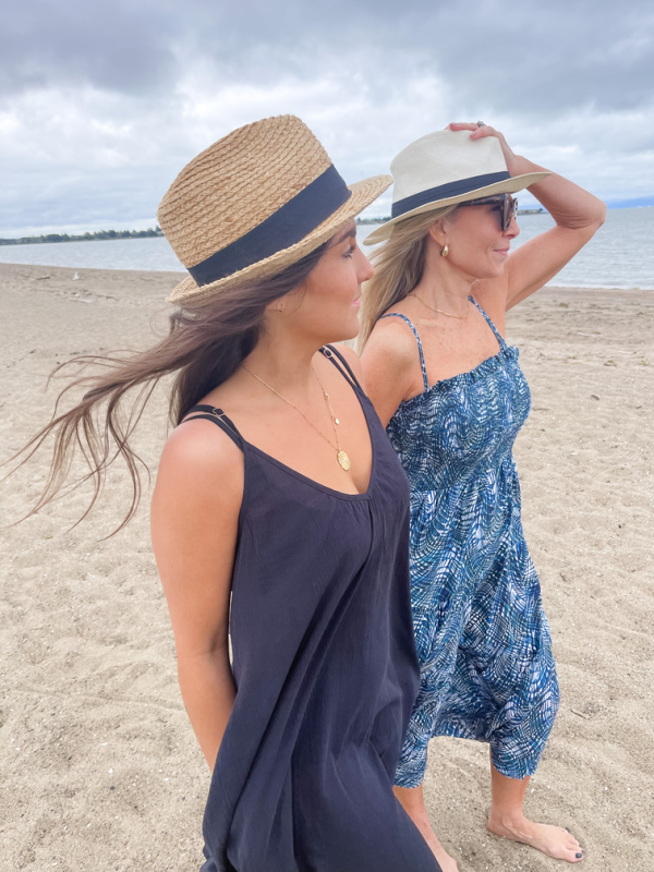 Two women wearing hats and Change of Scenery dresses walking on beach.