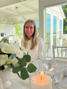 Woman sitting at table with white flowers.