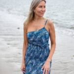 Woman wearing Change of Scenery one-piece bathing suit and matching skirt on beach.