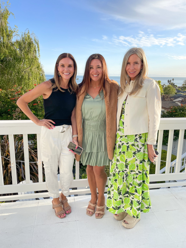 Tree women standing on deck overlooking Pacific Ocean.