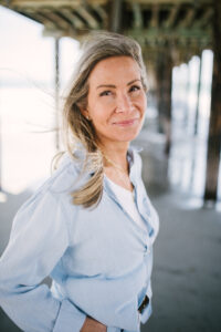 Woman standing on beach under pier.
