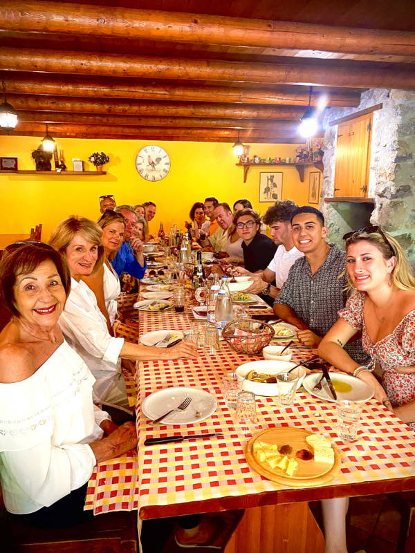 Friends sitting around farmhouse table in Italy.