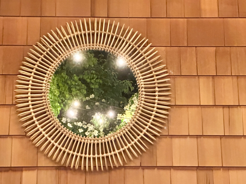 Round outdoor mirror reflecting the garden.