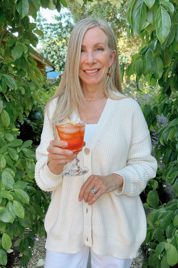 Woman standing in the garden with Aperol Spritz.