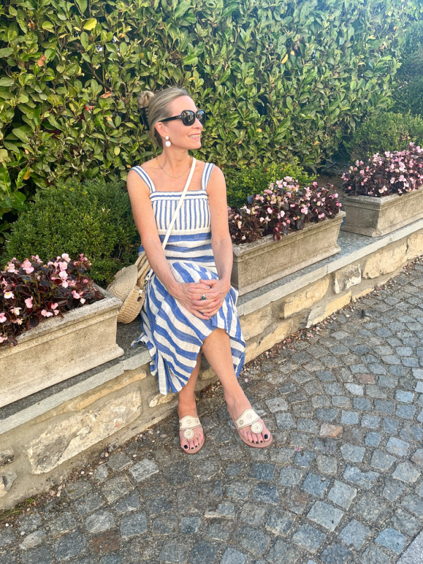 Woman in striped dress sitting on stone wall in Bellagio, Italy.