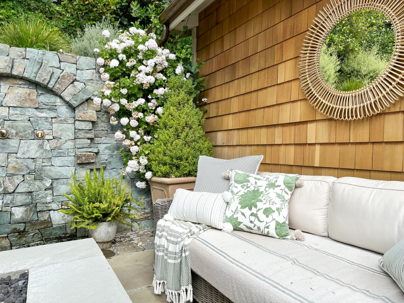 Patio sofa next to fire pit and water feature.