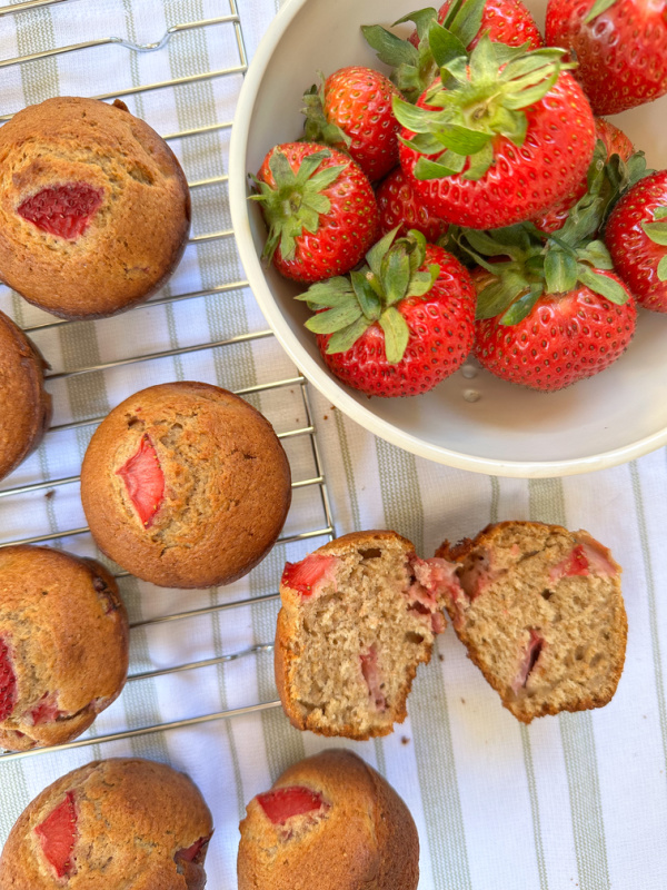 Strawberry muffins next to bowl of strawberries.