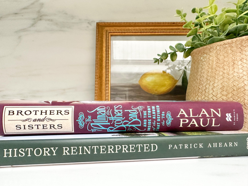 Two books sitting on counter alongside artwork and a plant.