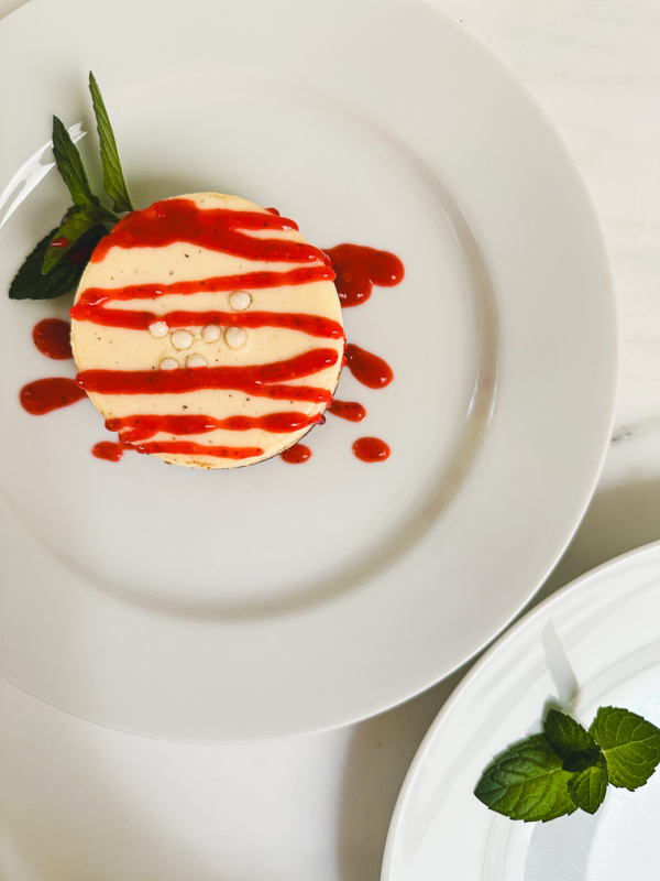 Small cheesecake drizzled with strawberry puree.