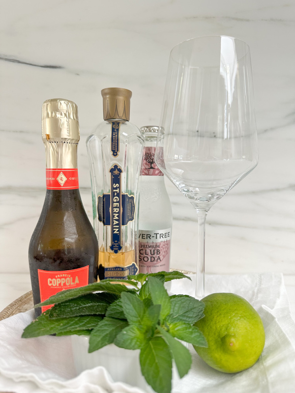 Ingredients for Hugo Spritz set on silver tray.