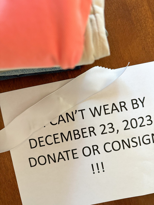 Stack of clothes next to sign, if I can't wear by ...