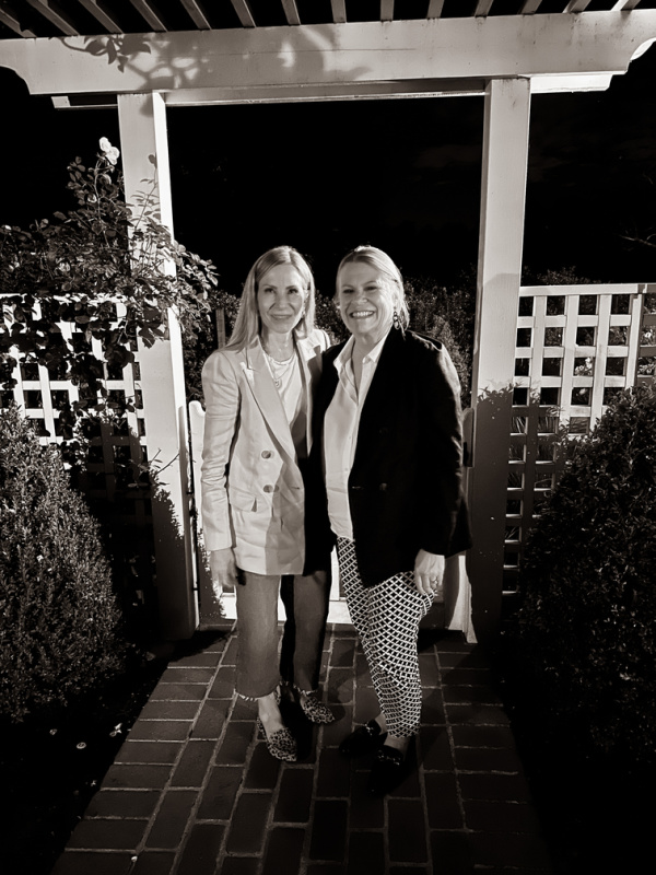 Two women standing in front of gate arbor.