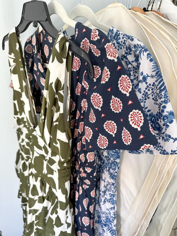 Three dresses hanging on rolling rack.