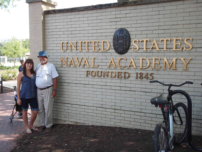 Grandpa and granddaughter standing outside gate to US Naval Academy.