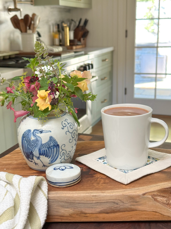 Alice Lane teak board and crane temple jar filled with flowers.
