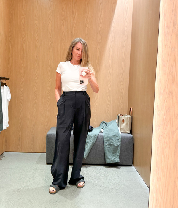 Woman in dressing room trying on Alo Yoga wear.