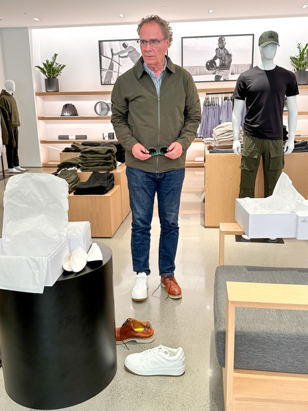 Man trying on shoes at Alo store.