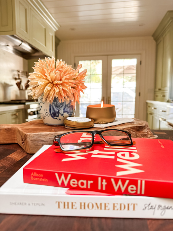 Books on kitchen island next to vase of dahlias and candle burning.