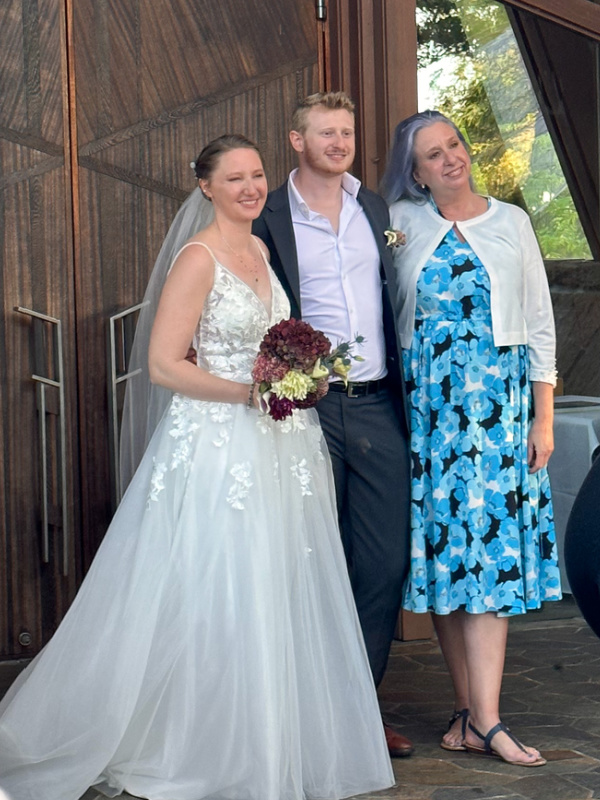Bride and groom with his mom outside wedding chapel.