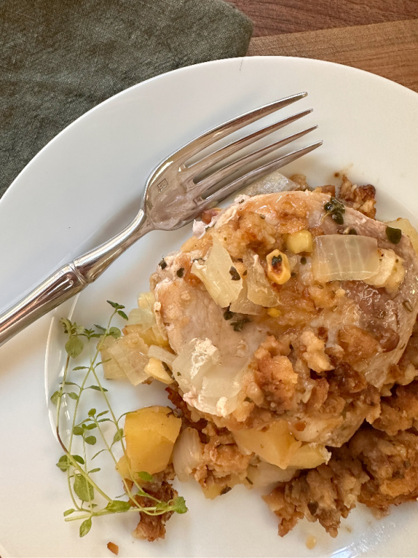 Plate with pork chop, stuffing and sprig of thyme.