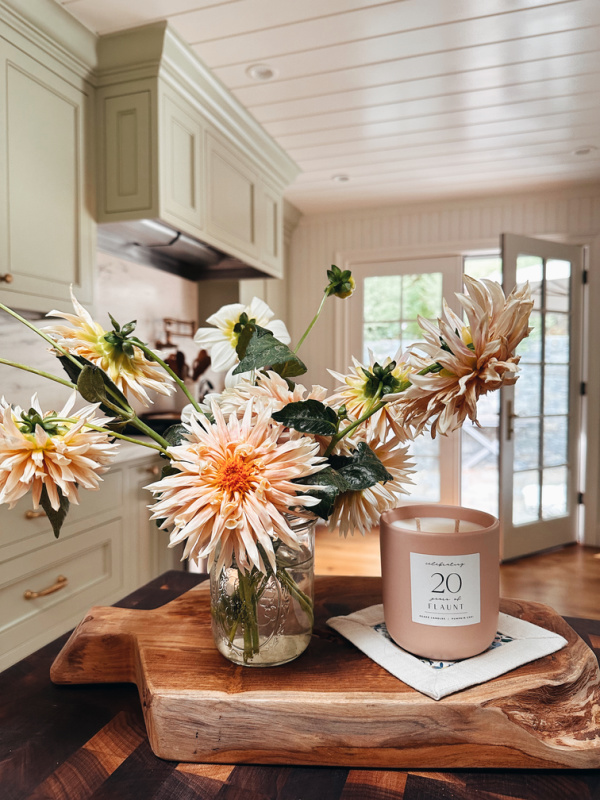 Arrangement of dahlias next to candle in kitchen island.