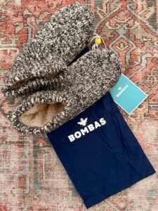 Bomba Slipper socks sitting on rug next to their carrier bag.