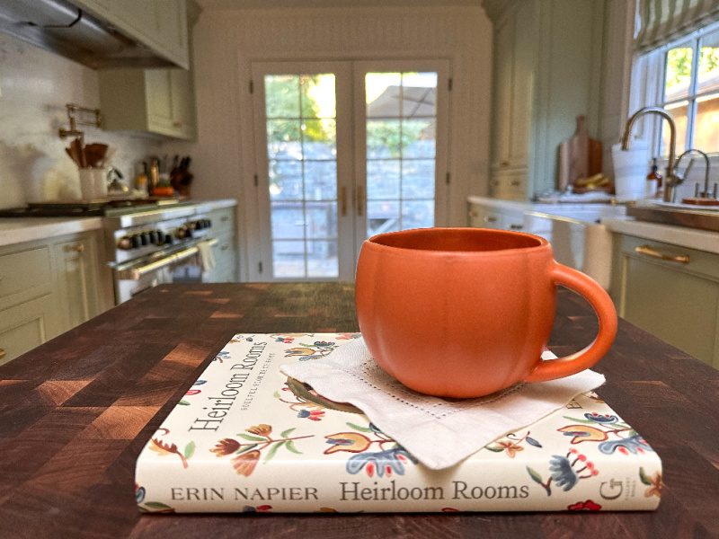 Pumpkin mug filled with cocoa sitting on book kitchen island.