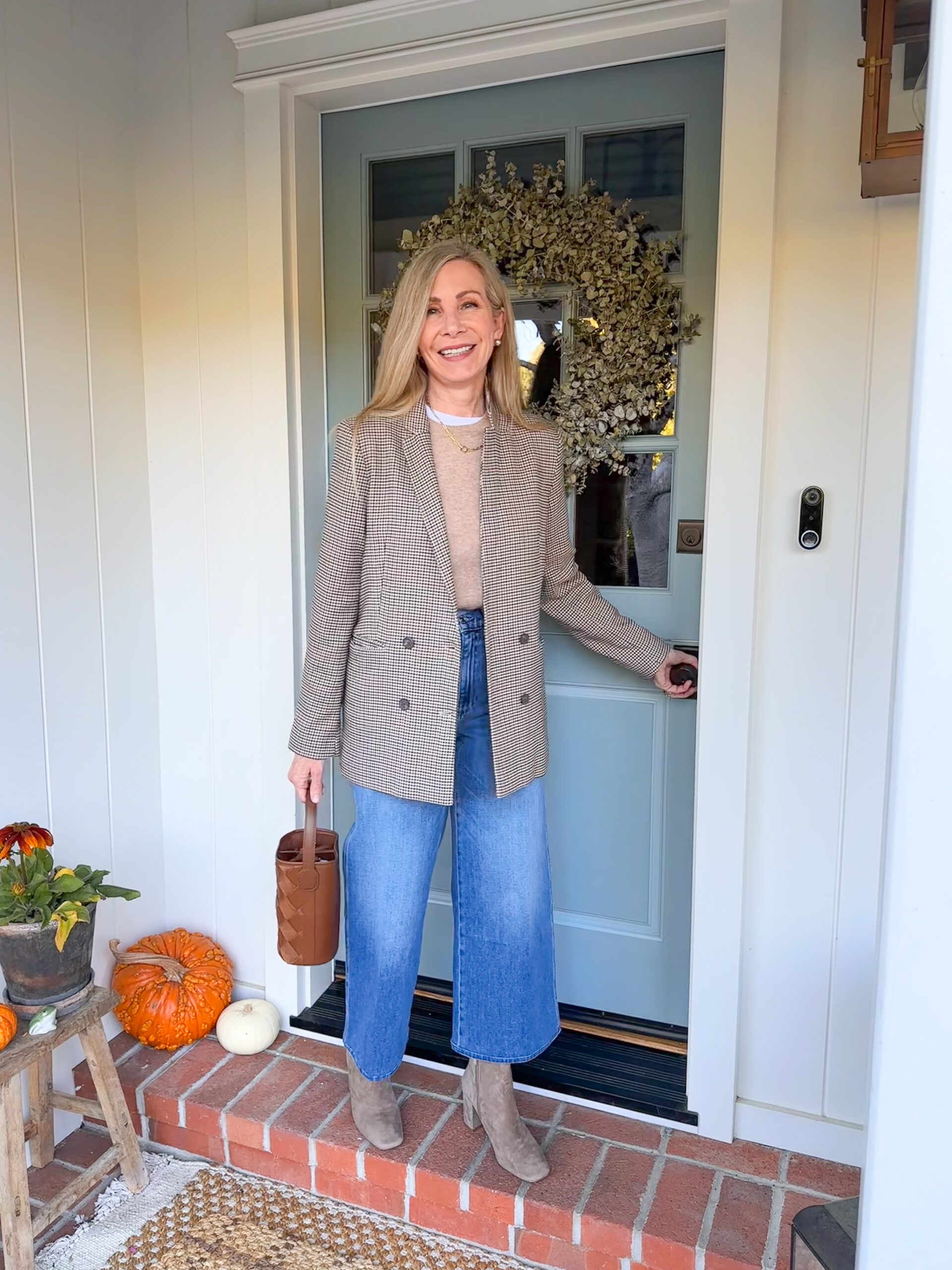 Woman on brick porch entering blue Dutch door.