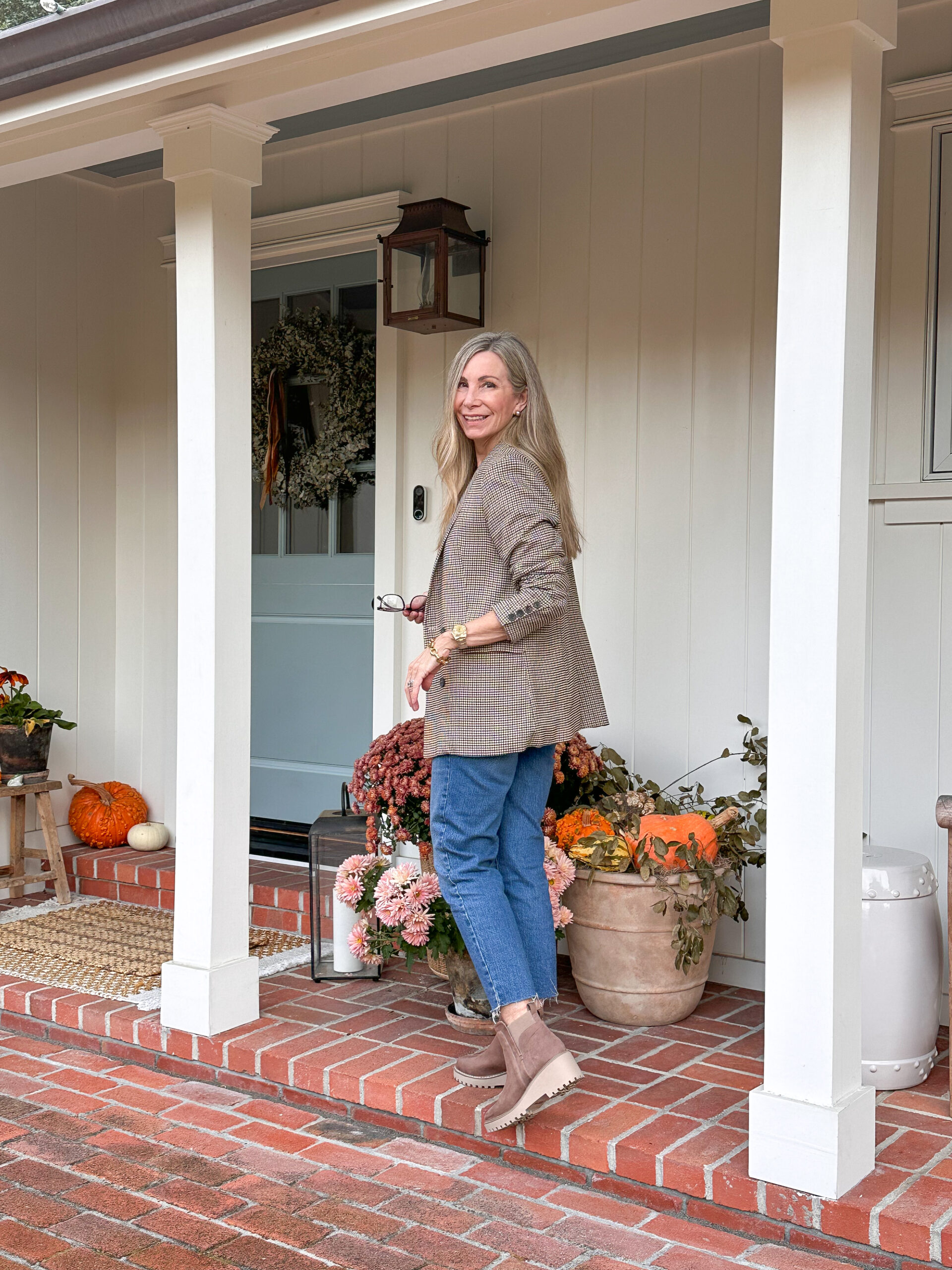 Woman walking toward front door on brick porch.