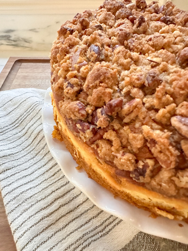 Pumpkin Coffee Cake on a white cake stand next to green and white tea towel.