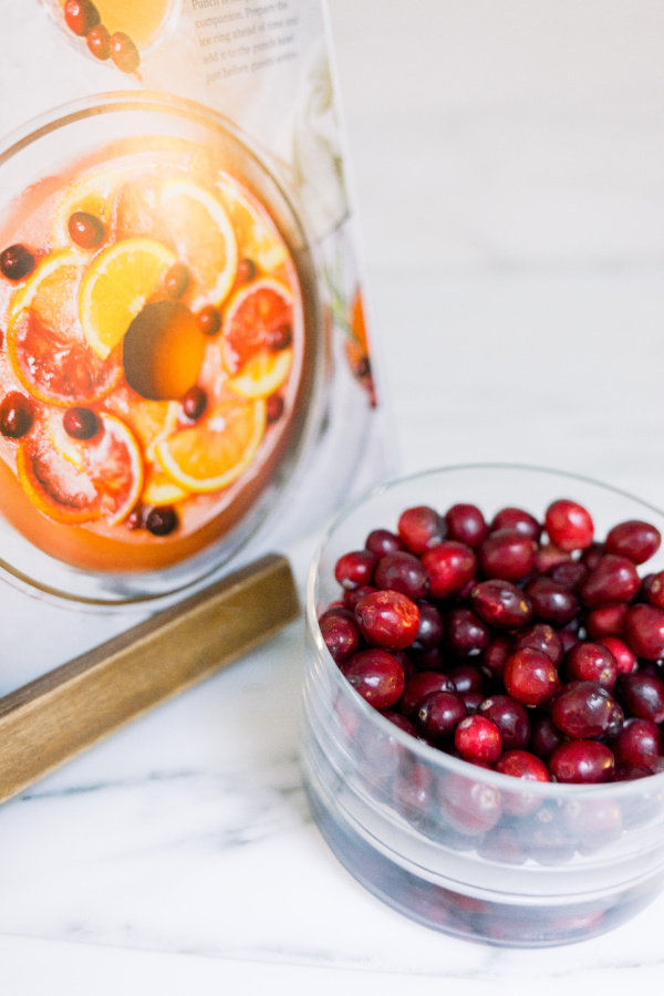 Cookbook on stand next to bowl of cranberries.
