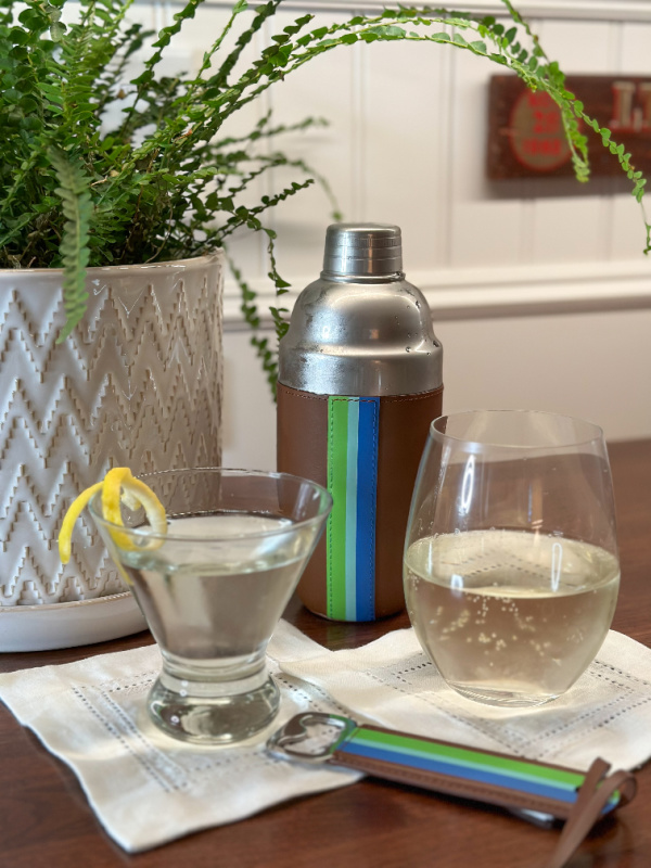 Martini and wine spritzer on bar alongside Ivy Cove cocktail shaker and bottle opener. 