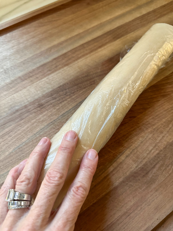 Hand holding tube of cookie dough.