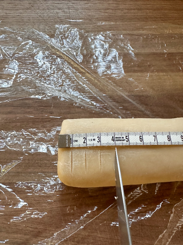 Cookie dough with tape measure on top and knife cutting disks.