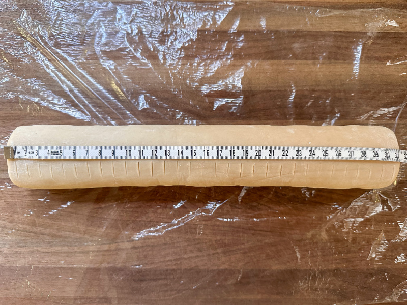 Tube of cookie dough with tape measure laying across it.