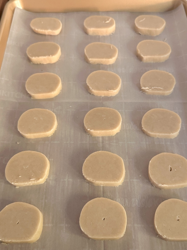 Shortbread cookie dough rounds on parchment lined cookie sheet.