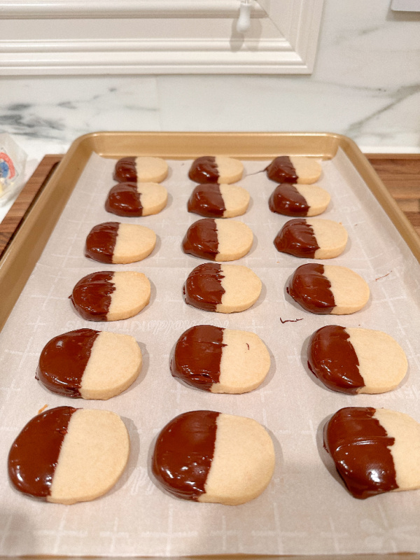 Shortbread cookies dipped in chocolate setting on a cookie sheet.